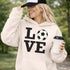 Hoodie with bold LOVE design featuring a soccer ball replacing the O, worn by woman holding coffee cup outdoors