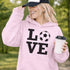 Hoodie with bold LOVE design featuring a soccer ball replacing the O, worn by woman holding coffee cup outdoors
