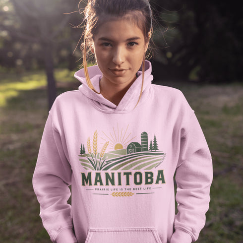 person wearing manitoba prairie life hoodie with farm and wheat field design standing in prairie field