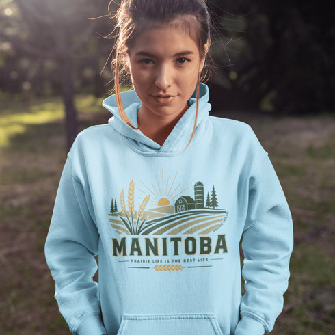 person wearing manitoba prairie life hoodie with farm and wheat field design standing in prairie field