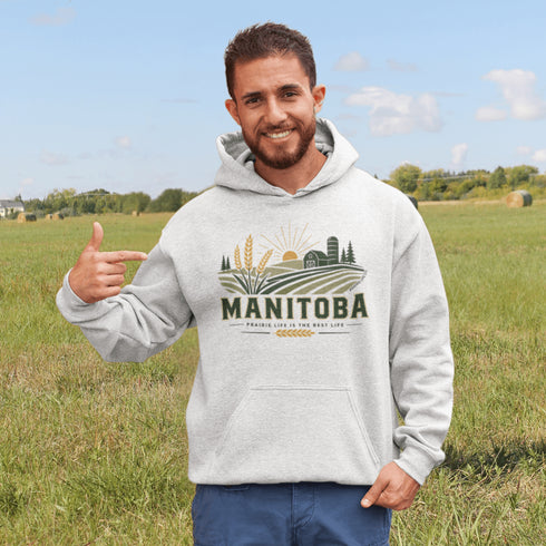 person wearing manitoba prairie life hoodie with farm and wheat field design standing in prairie field