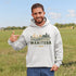 person wearing manitoba prairie life hoodie with farm and wheat field design standing in prairie field