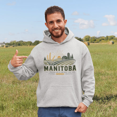 person wearing manitoba prairie life hoodie with farm and wheat field design standing in prairie field