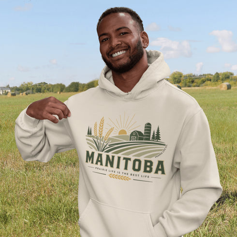 person wearing manitoba prairie life hoodie with farm and wheat field design standing in prairie field