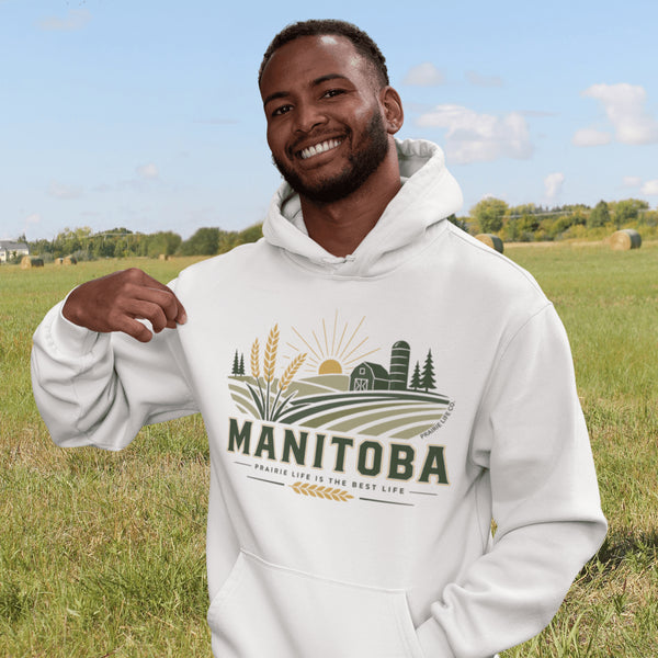 person wearing manitoba prairie life hoodie with farm and wheat field design standing in prairie field