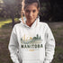 person wearing manitoba prairie life hoodie with farm and wheat field design standing in prairie field