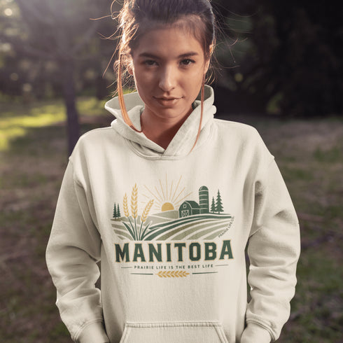 person wearing manitoba prairie life hoodie with farm and wheat field design standing in prairie field