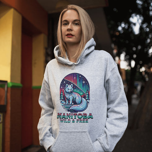 Embrace the beauty of the North with our Manitoba - Wild & Free Hoodie, featuring a stunning graphic of an arctic fox beneath the shimmering northern lights.