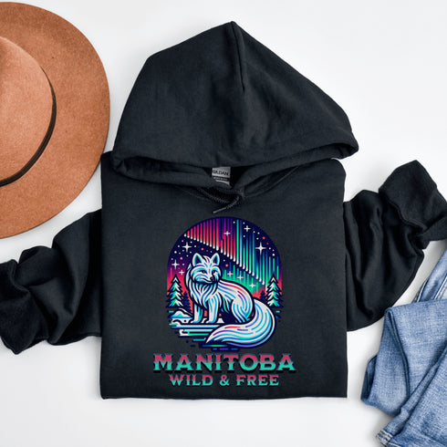 Embrace the beauty of the North with our Manitoba - Wild & Free Hoodie, featuring a stunning graphic of an arctic fox beneath the shimmering northern lights.