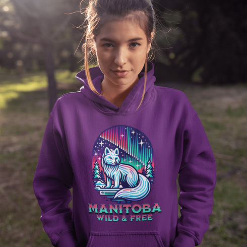 Embrace the beauty of the North with our Manitoba - Wild & Free Hoodie, featuring a stunning graphic of an arctic fox beneath the shimmering northern lights.