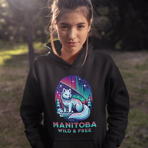 Embrace the beauty of the North with our Manitoba - Wild & Free Hoodie, featuring a stunning graphic of an arctic fox beneath the shimmering northern lights.