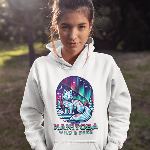 Embrace the beauty of the North with our Manitoba - Wild & Free Hoodie, featuring a stunning graphic of an arctic fox beneath the shimmering northern lights.