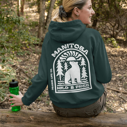 This cozy hoodie features a bold graphic of a bear surrounded by pine trees and rising sun—capturing the spirit of Manitoba’s rugged landscapes and Prairie Life culture.
