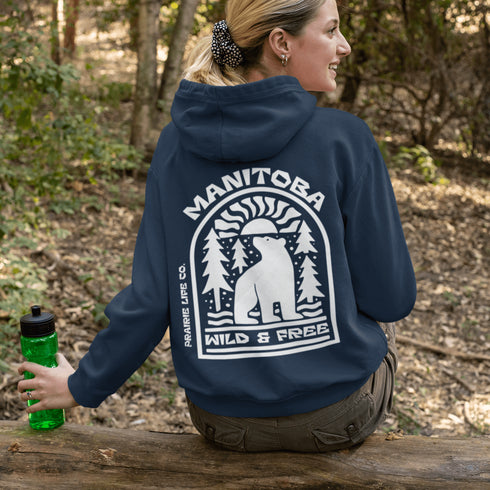 This cozy hoodie features a bold graphic of a bear surrounded by pine trees and rising sun—capturing the spirit of Manitoba’s rugged landscapes and Prairie Life culture.