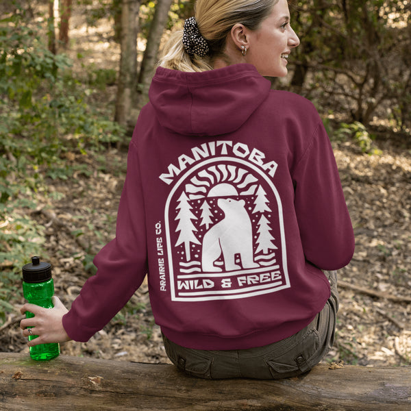 This cozy hoodie features a bold graphic of a bear surrounded by pine trees and rising sun—capturing the spirit of Manitoba’s rugged landscapes and Prairie Life culture.