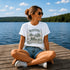 Woman sitting on a dock by a lake wearing a 'Manitoba Canada' t-shirt.