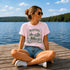 Woman sitting on a dock by a lake wearing a pink 'Manitoba Canada' t-shirt.