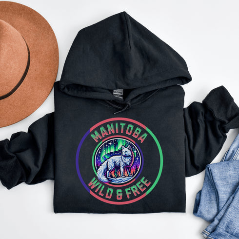 Unleash your wild side with our Manitoba – Wild & Free hoodie, featuring an enchanting graphic of an arctic fox beneath the dazzling northern lights.