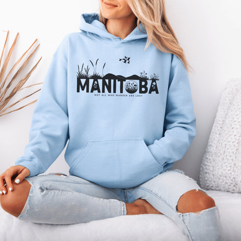 Featuring a prairie landscape, the design showcases wildflowers and prairie grasses blooming from the letters "Manitoba," artfully integrated into the scene.