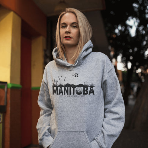 Featuring a prairie landscape, the design showcases wildflowers and prairie grasses blooming from the letters "Manitoba," artfully integrated into the scene.