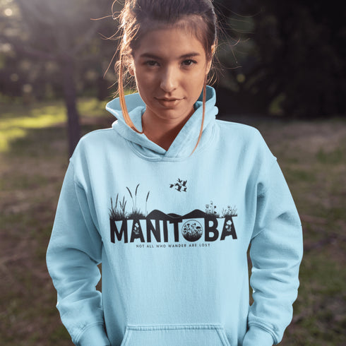 Featuring a prairie landscape, the design showcases wildflowers and prairie grasses blooming from the letters "Manitoba," artfully integrated into the scene.