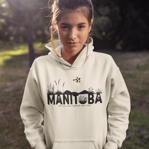 Featuring a prairie landscape, the design showcases wildflowers and prairie grasses blooming from the letters "Manitoba," artfully integrated into the scene.