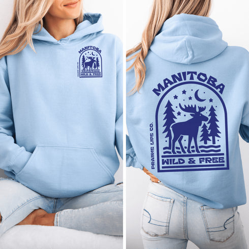 This Manitoba hoodie captures the beauty of Canada’s backcountry with a moose silhouette surrounded by starlit skies, tall evergreens, and a crescent moon.