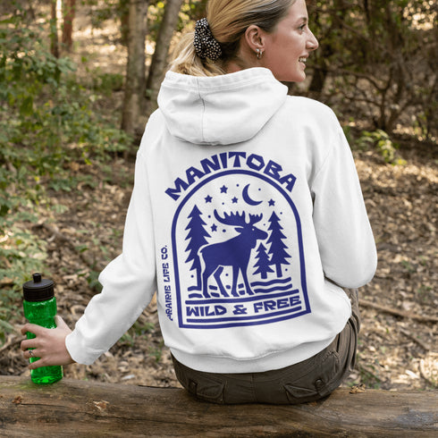 This Manitoba hoodie captures the beauty of Canada’s backcountry with a moose silhouette surrounded by starlit skies, tall evergreens, and a crescent moon.