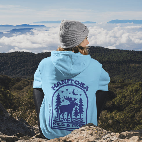 This Manitoba hoodie captures the beauty of Canada’s backcountry with a moose silhouette surrounded by starlit skies, tall evergreens, and a crescent moon.