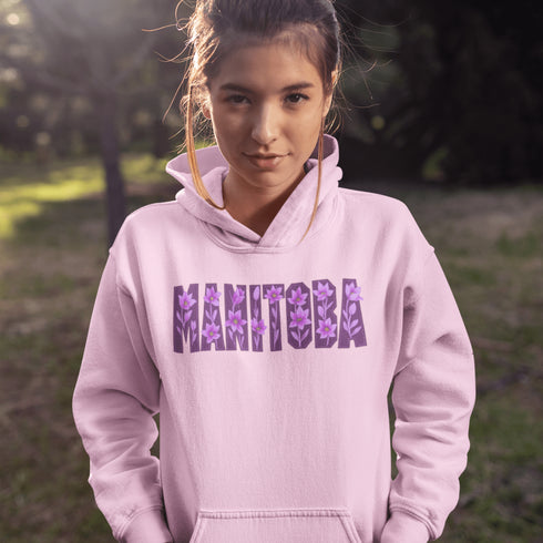Celebrate the beauty of the prairies with our Manitoba Hoodie, featuring bold lettering filled with delicate purple prairie crocus flowers.
