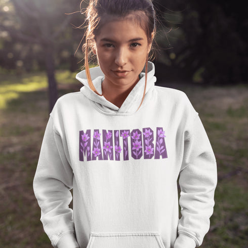Celebrate the beauty of the prairies with our Manitoba Hoodie, featuring bold lettering filled with delicate purple prairie crocus flowers.