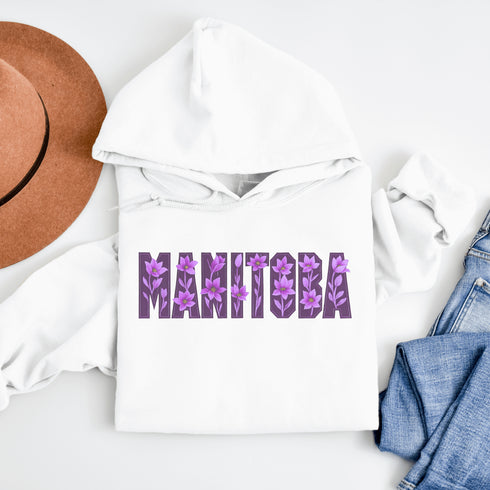 Celebrate the beauty of the prairies with our Manitoba Hoodie, featuring bold lettering filled with delicate purple prairie crocus flowers.