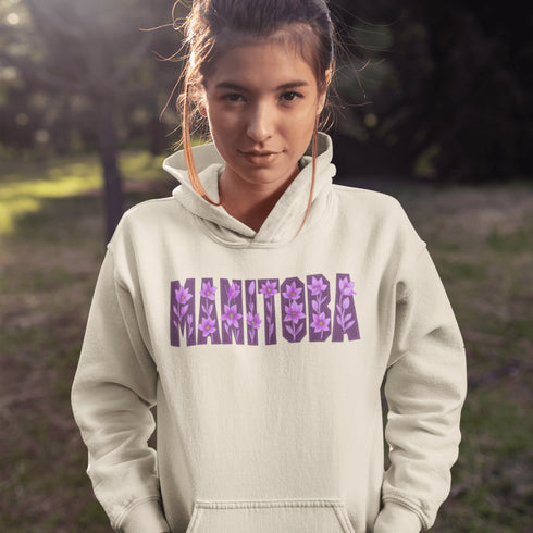 Celebrate the beauty of the prairies with our Manitoba Hoodie, featuring bold lettering filled with delicate purple prairie crocus flowers.