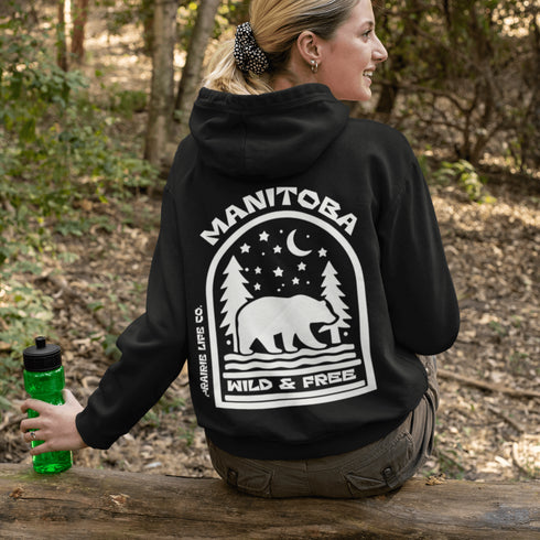 This cozy hoodie features a bold back print of a bear walking beneath a crescent moon and pine trees—capturing everything we love about Canada’s wilderness.