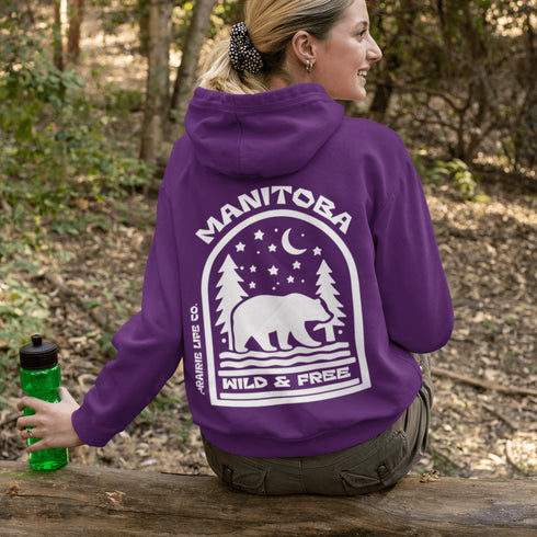 This cozy hoodie features a bold back print of a bear walking beneath a crescent moon and pine trees—capturing everything we love about Canada’s wilderness.