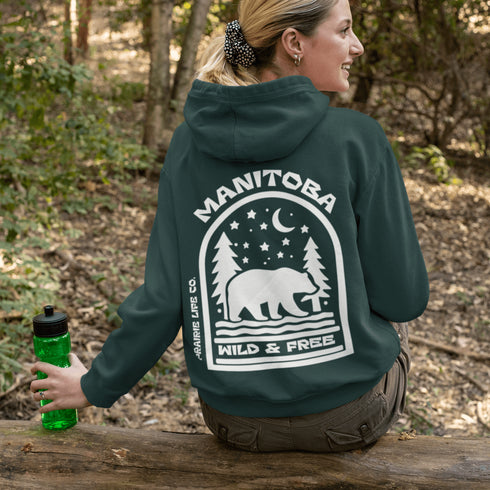 This cozy hoodie features a bold back print of a bear walking beneath a crescent moon and pine trees—capturing everything we love about Canada’s wilderness.
