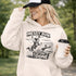 Woman wearing a Messy Bun & Getting It Done soccer mom hoodie with vintage soccer design, holding coffee outdoors