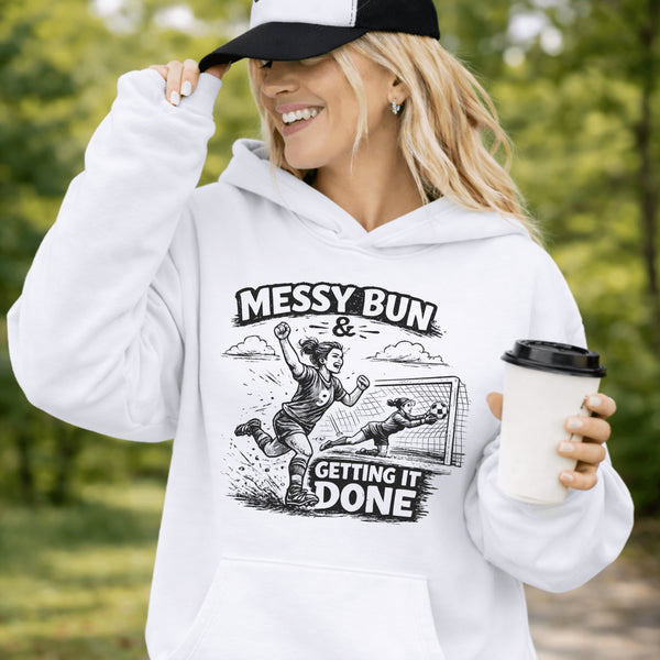 Woman wearing a light blue Messy Bun & Getting It Done soccer mom hoodie with vintage soccer design, holding coffee outdoors