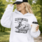 Woman wearing a light blue Messy Bun & Getting It Done soccer mom hoodie with vintage soccer design, holding coffee outdoors