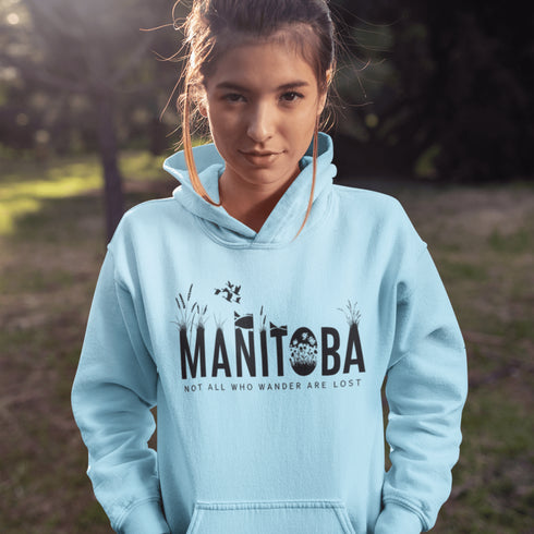 Featuring a serene prairie landscape, the design captures the essence of the heartland with wildflowers and prairie grasses growing out of the letters Manitoba.