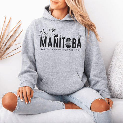 Featuring a serene prairie landscape, the design captures the essence of the heartland with wildflowers and prairie grasses growing out of the letters Manitoba.