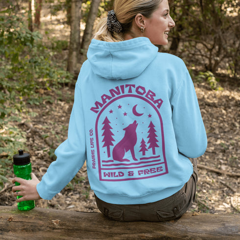 Featuring a howling wolf surrounded by pine trees, twinkling stars, and a crescent moon, this hoodie captures the magic of the northern wilderness.