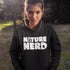 Person wearing a black hoodie with 'Nature Nerd' text in a natural setting