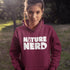Person wearing a maroon hoodie with 'Nature Nerd' text in a natural setting
