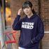 Person wearing a navy hoodie with 'Nature Nerd' text, standing outdoors against a brick wall.