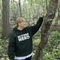 Person wearing a 'Nature Nerd' hoodie interacting with a bird in a forest.