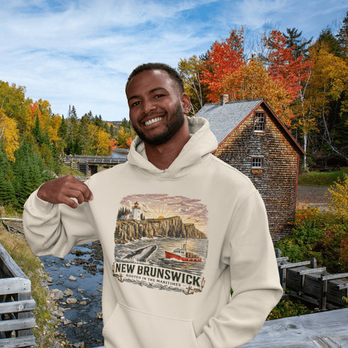 Man wearing a hoodie with New Brunswick design in front of a scenic autumn landscape.