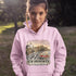 Person wearing a pink hoodie with a New Brunswick design outdoors