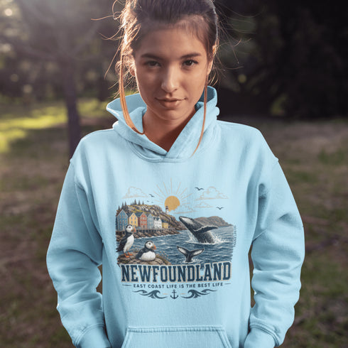Person wearing a light blue hoodie with a Newfoundland design outdoors.