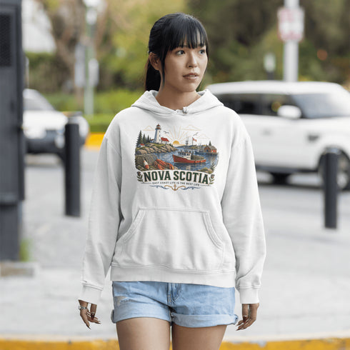 Nova Scotia hoodie with lighthouse coastal fishing village graphic worn by model outdoors near ocean cliffs